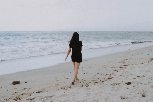 Одинокая девушка идет по берегу океана