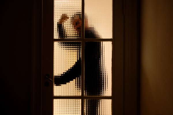 Агрессивный мужчина стоит за стеклянной дверью